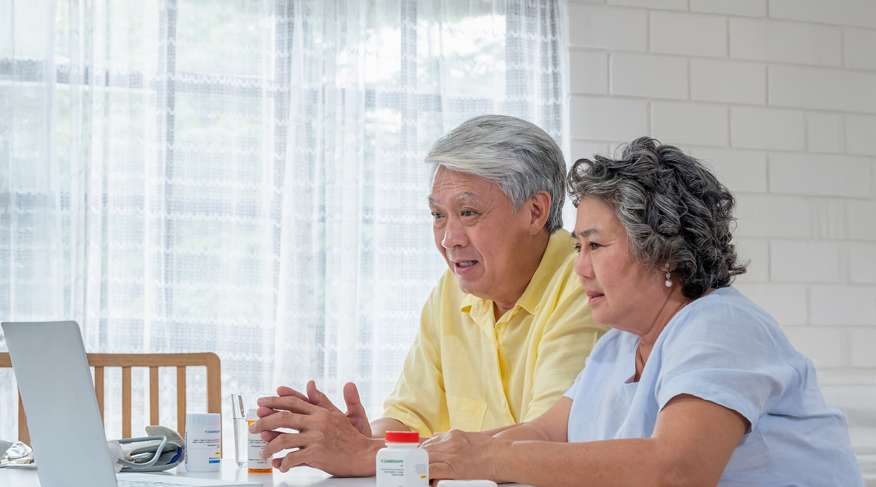Couple sitting on dining table with laptop